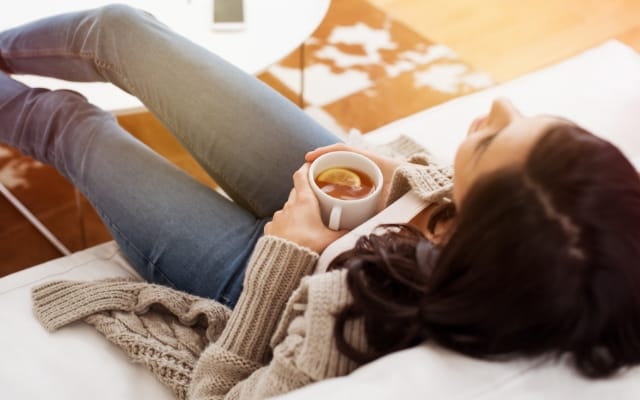 Mujer descansa en el sofá con una taza de té