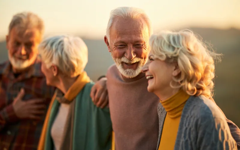 Personas mayores sonrientes al aire libre con la luz del atardecer