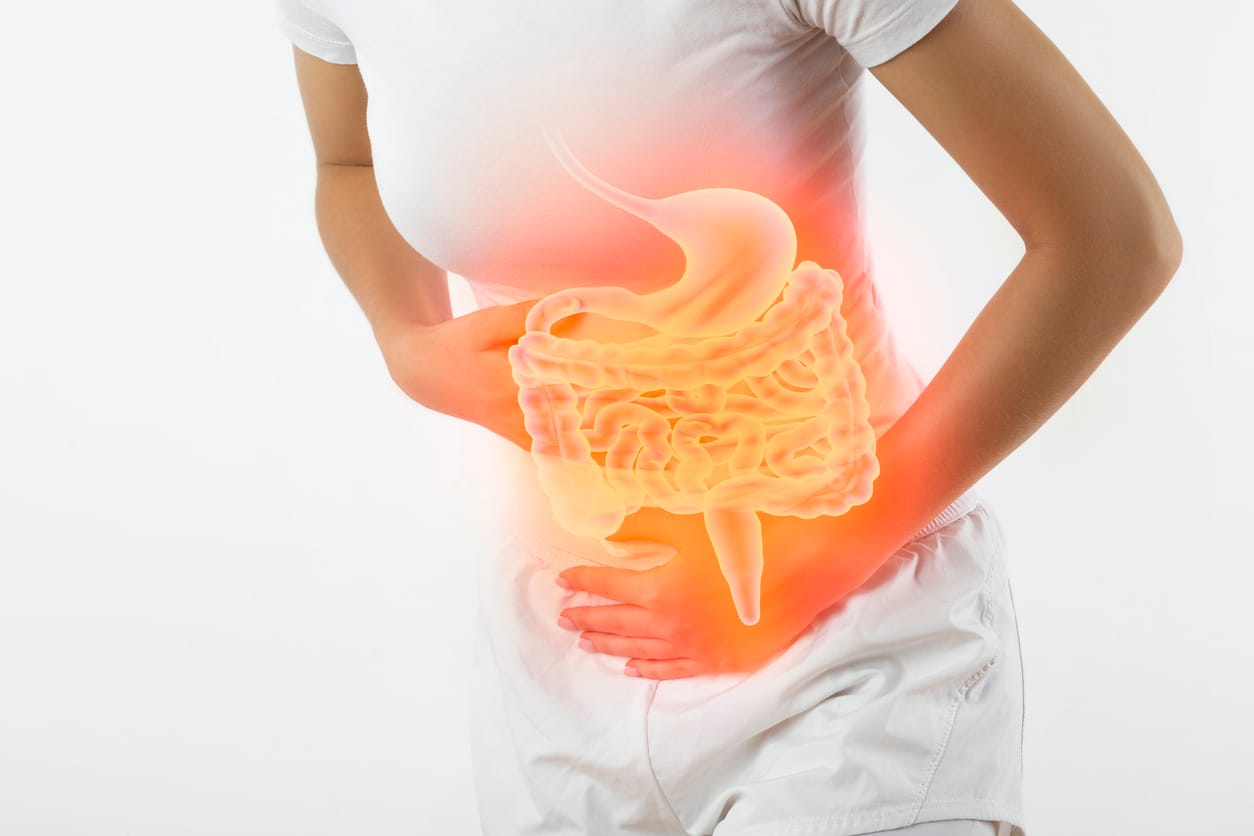 Mujer con dolor abdominal e ilustración del aparato digestivo iluminada en rojo
