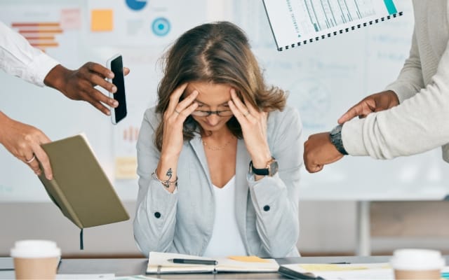 Mujer estresada en el trabajo se sujeta la cabeza con ambas manos