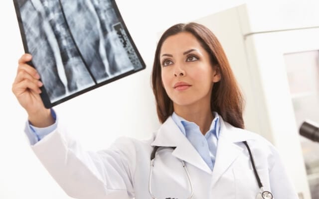 Médica observa una radiografía de la columna vertebral