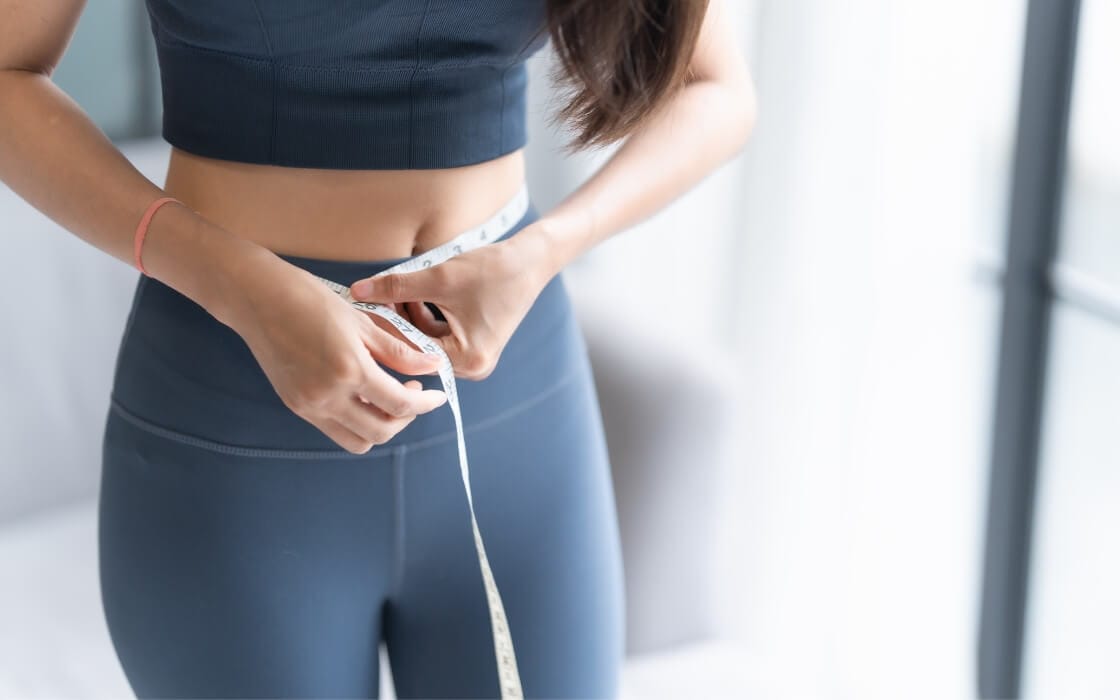 Mujer se mide el perímetro abdominal con una cinta métrica