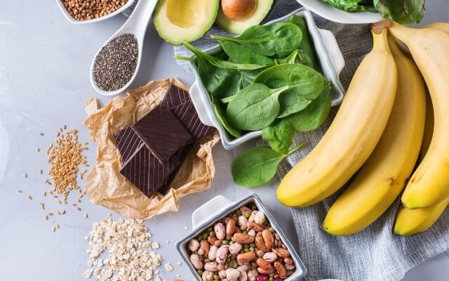 Alimentos ricos en magnesio como espinacas, plátanos, frutos secos y chocolate negro