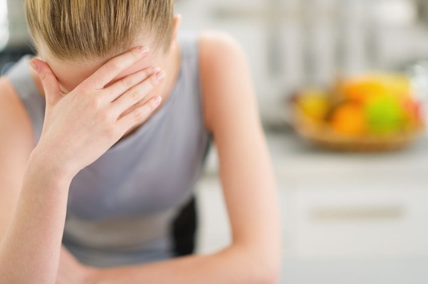 Mujer se cubre la cara con la mano en la cocina
