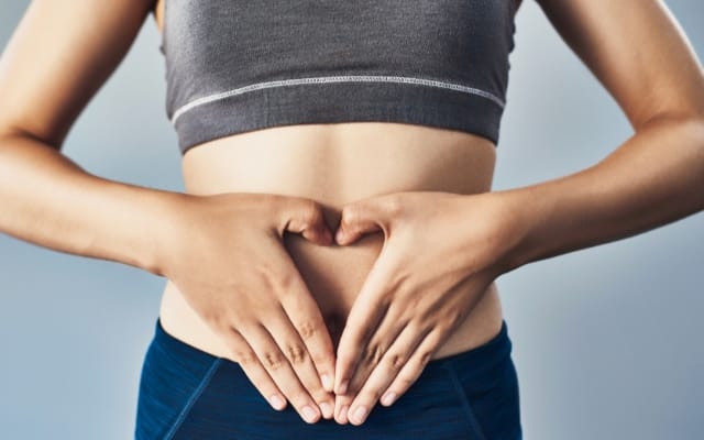 Mujer se coloca las manos sobre el abdomen
