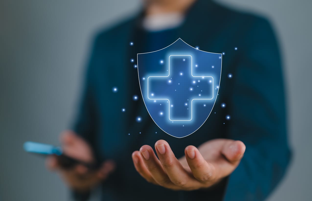 Hombre sostiene un escudo azul con una cruz como símbolo de protección de la salud