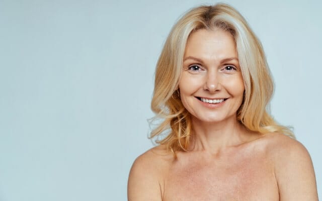 Mujer sonriente de cabello rubio con la piel del rostro lisa