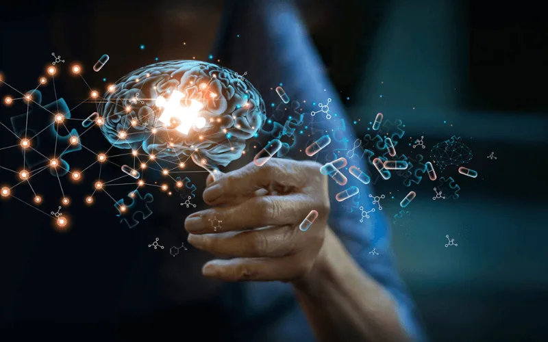 Ilustración de un cerebro luminoso con cápsulas y puntos de luz sobre una mano