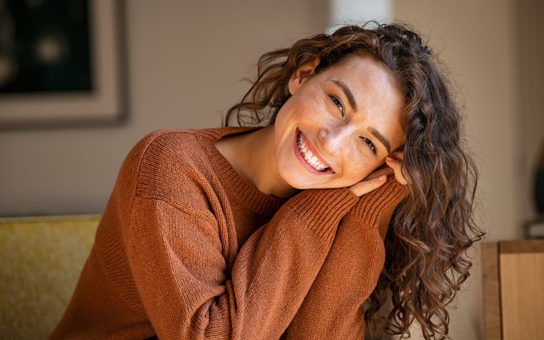 Mujer sonriente apoyada en el sofá