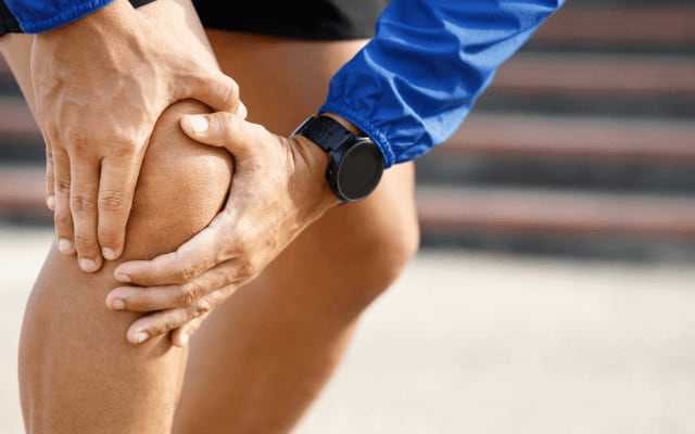 Unas manos sujetan una rodilla dolorida